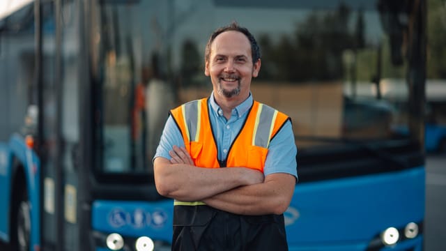 Busfahrer mit Warnweste vor seinem Fahrzeug